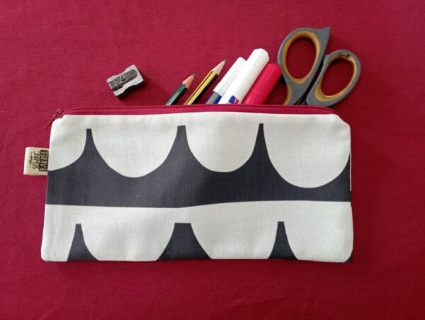 Ein Federmäppchen aus Canvas mit einem schwarz-weißen geometrischen Muster, gefüllt mit einer Schere, Filzstiften, Bleistiften und einem Radiergummi.